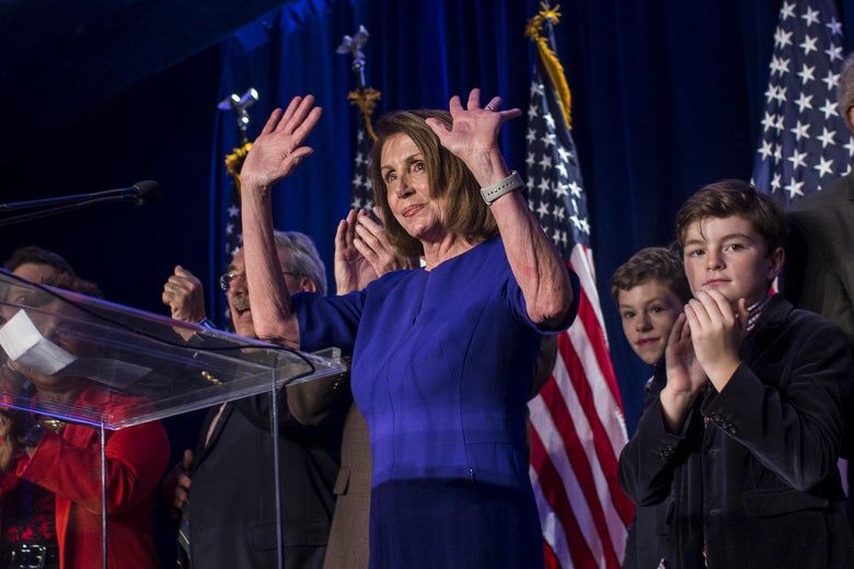 Nancy Pelosi raises her hands from behind a podium.